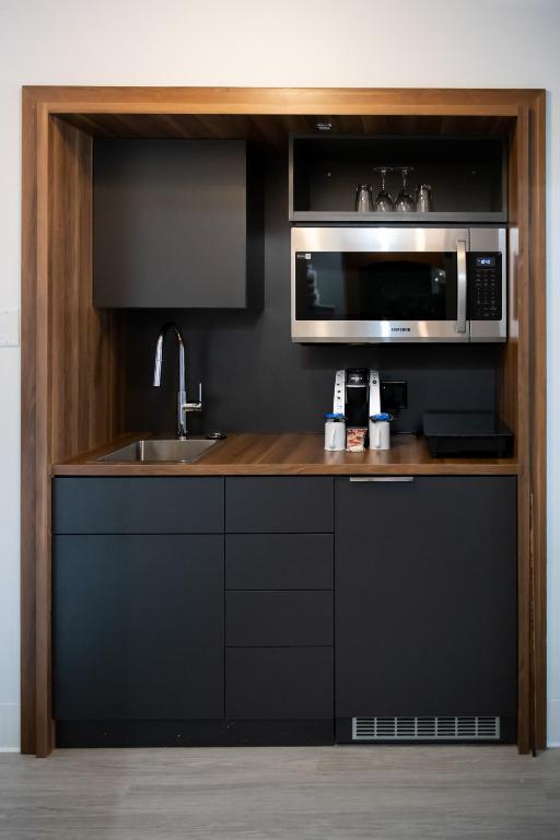 a kitchen with a sink and a microwave at Auberge Des Îles in Saint-Gédéon