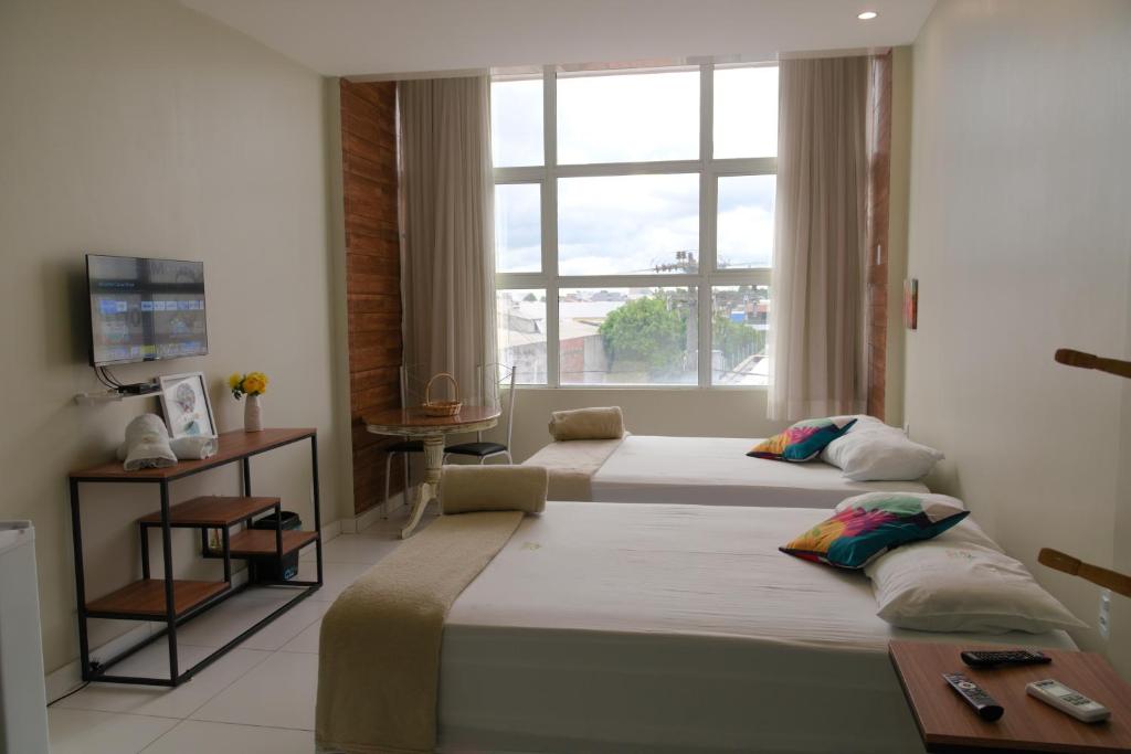 two beds in a room with a window at Pousada Vasconcelos Tianguá in Tianguá
