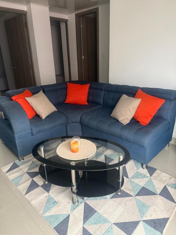 a blue couch with orange pillows and a coffee table at En el corazon de Dosquebradas in Dosquebradas