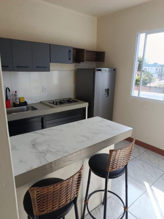 a kitchen with a counter and two bar stools at Kitnet 1 quarto in Torres