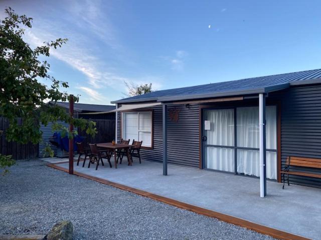 a house with a patio with a table and benches at Omarama Crib Spotless Scenic Base for Families in Omarama