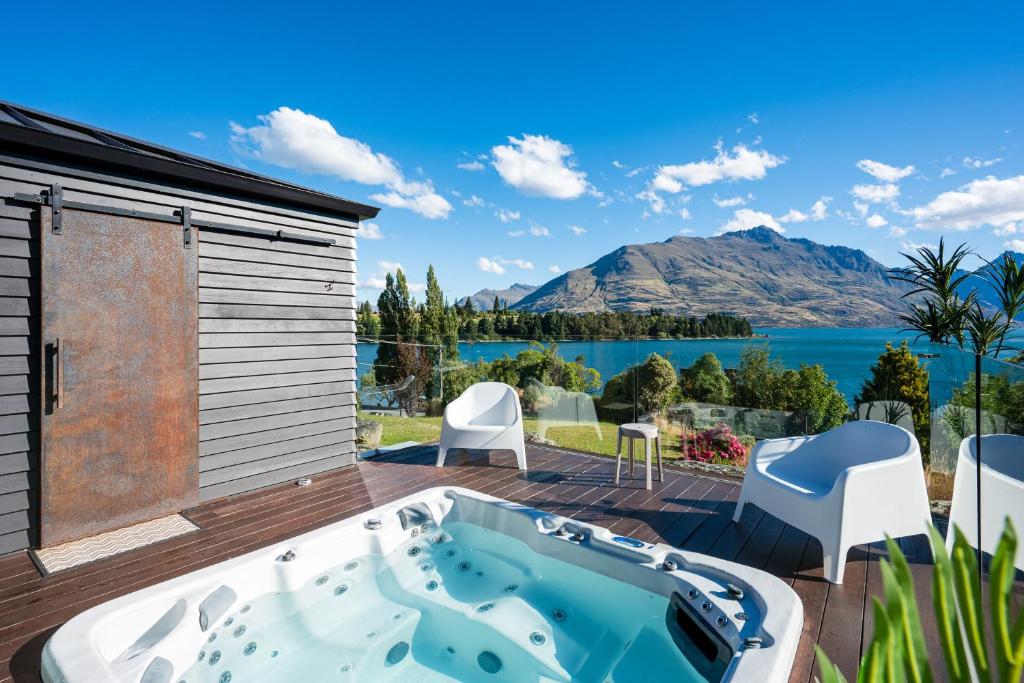 a hot tub on a deck with a view of the water at Blackwood Lakeview Retreat in Queenstown