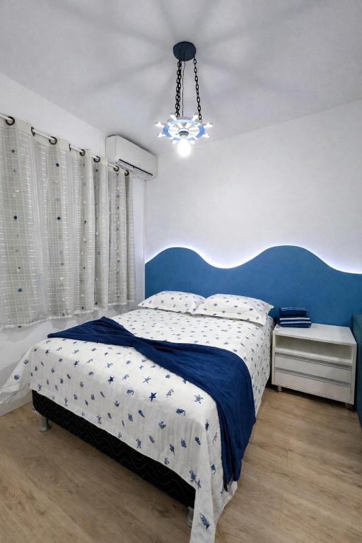 a bedroom with a blue and white bed and a chandelier at Flat Aeroporto - Estrada do coco - Lauro de Freitas M in Lauro de Freitas