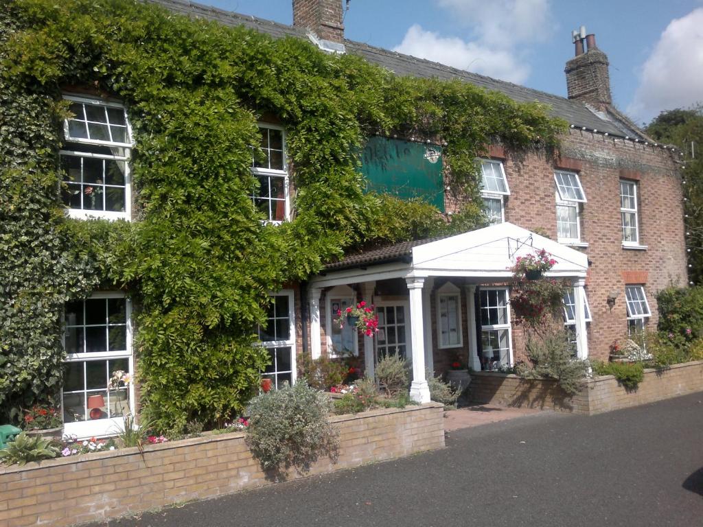 una casa ricoperta di edera con una veranda bianca di The Andel a Kings Lynn