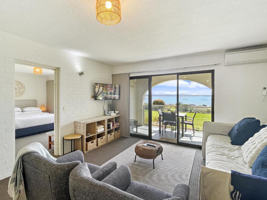 a living room with a couch and a bed and a table at Beachside Apartment Overlooking Caseys Beach in Batehaven