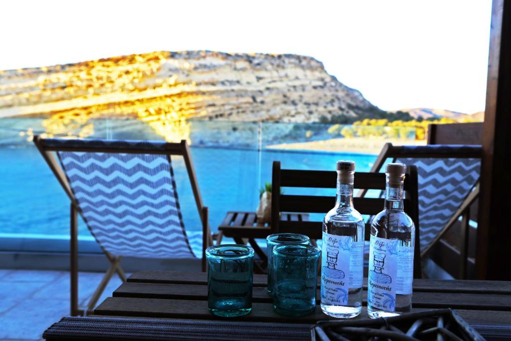 due bottiglie e bicchieri su un tavolo con vista di Matala Caves a Mátala