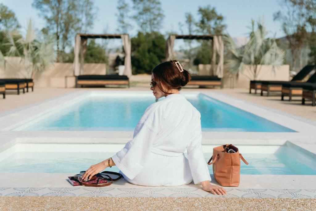 a woman sitting next to a swimming pool at Equ Hotel Boutique in El Porvenir