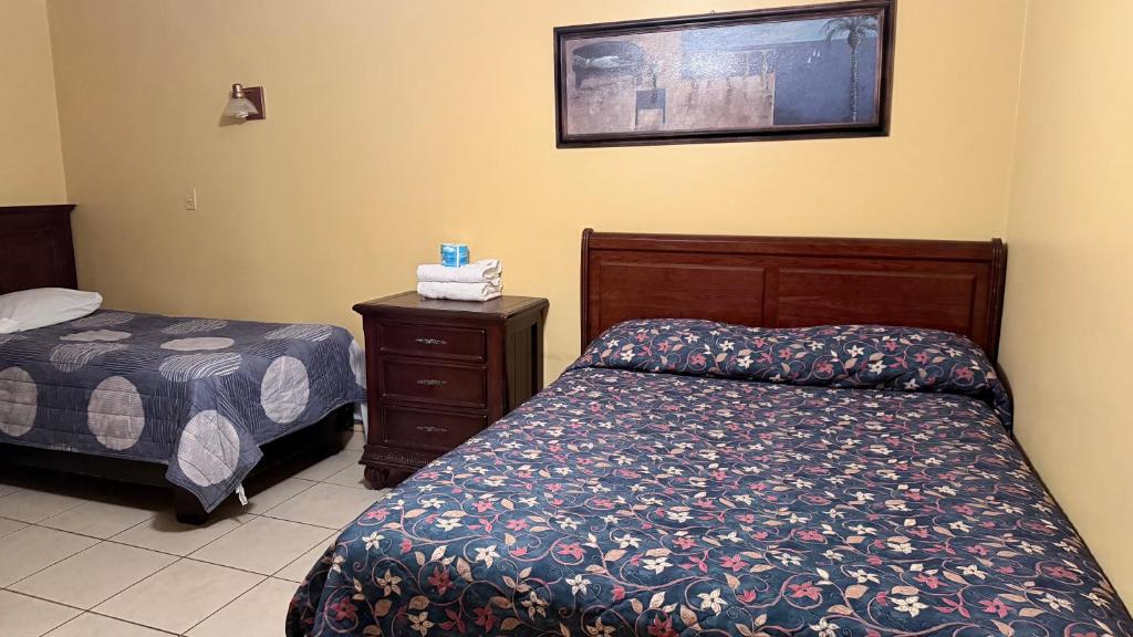 a hotel room with two beds and a night stand at Hotel Segovia in Tijuana