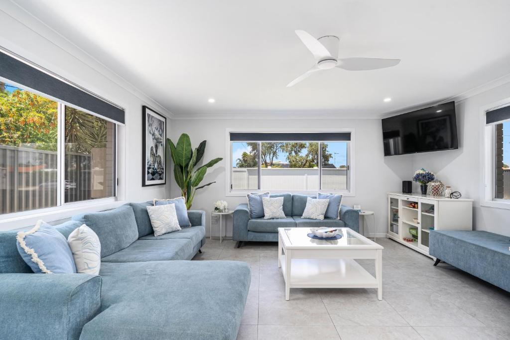 a living room with blue couches and a table at Pet Friendly Beach House with pool - Sleeps 10 in Urangan