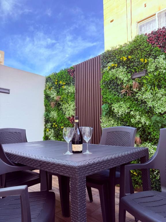 a table with a bottle of wine and two glasses at Spielberg - Garage, Outdoor Area, Close to Beach in Marsaskala
