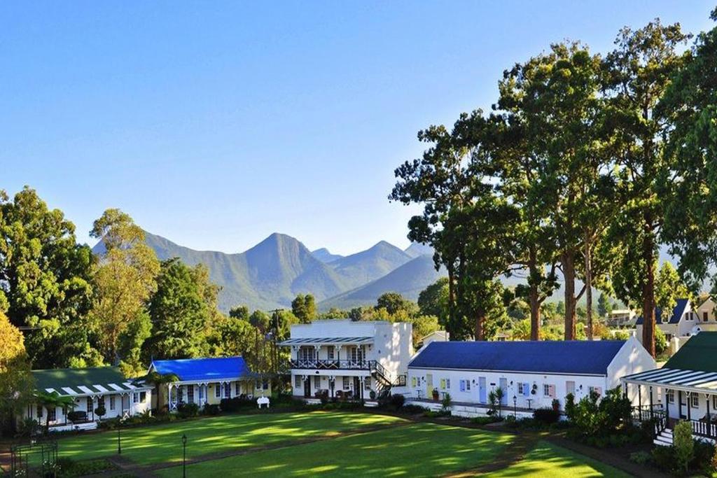 a large white house with trees and houses at Tsitsikamma Village Inn in Stormsrivier