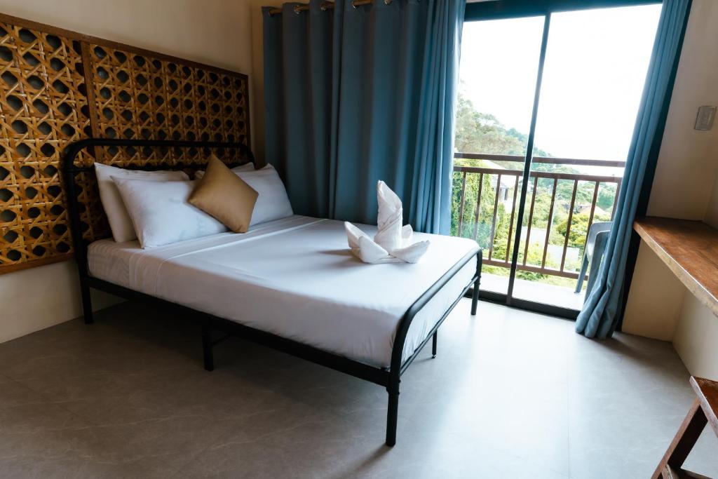 a bedroom with a bed with a large window at The Shack Hideaway by Mayumi Resorts in Mabini