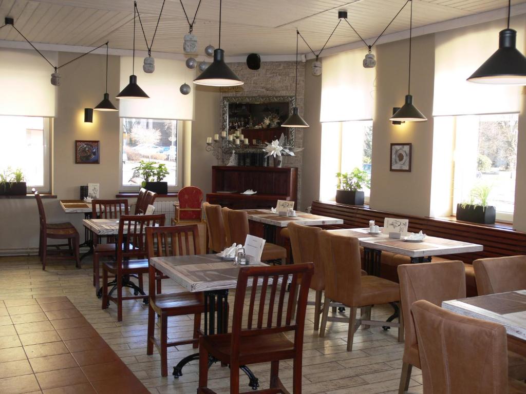 a dining room with tables and chairs and windows at Hotel Na Baste in Jablonec nad Nisou