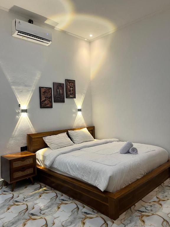 a bedroom with a bed and two lights on the wall at Mahoney Homestay in Kuta Lombok