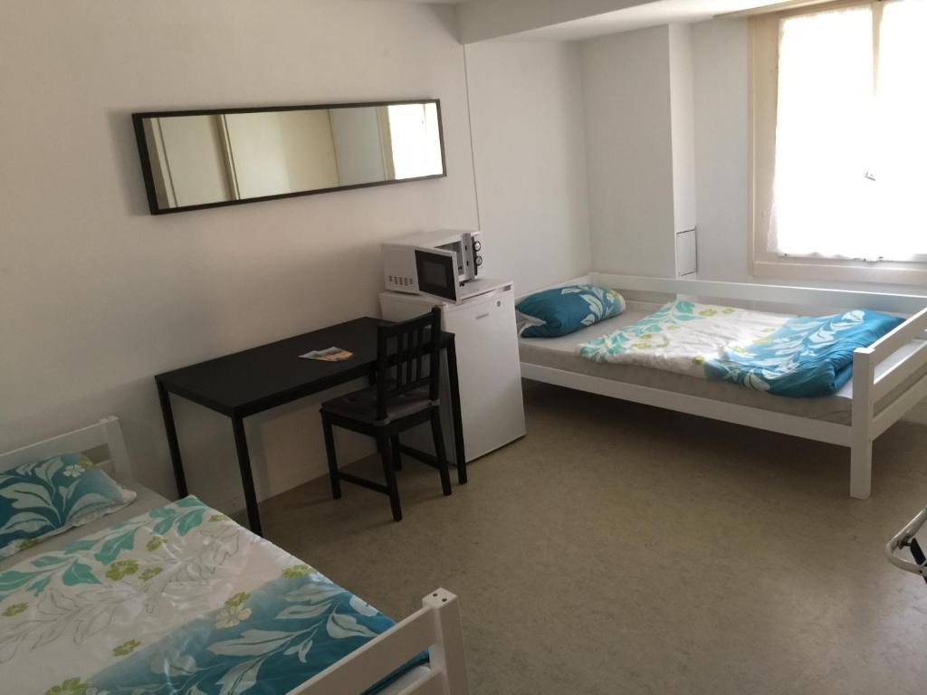 a room with two beds and a table and a mirror at Hostel Airport in Oberglatt