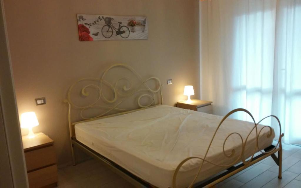 Casa Vacanze Zadina في تشيزيناتيكو: غرفة نوم بسرير ابيض ومصباحين