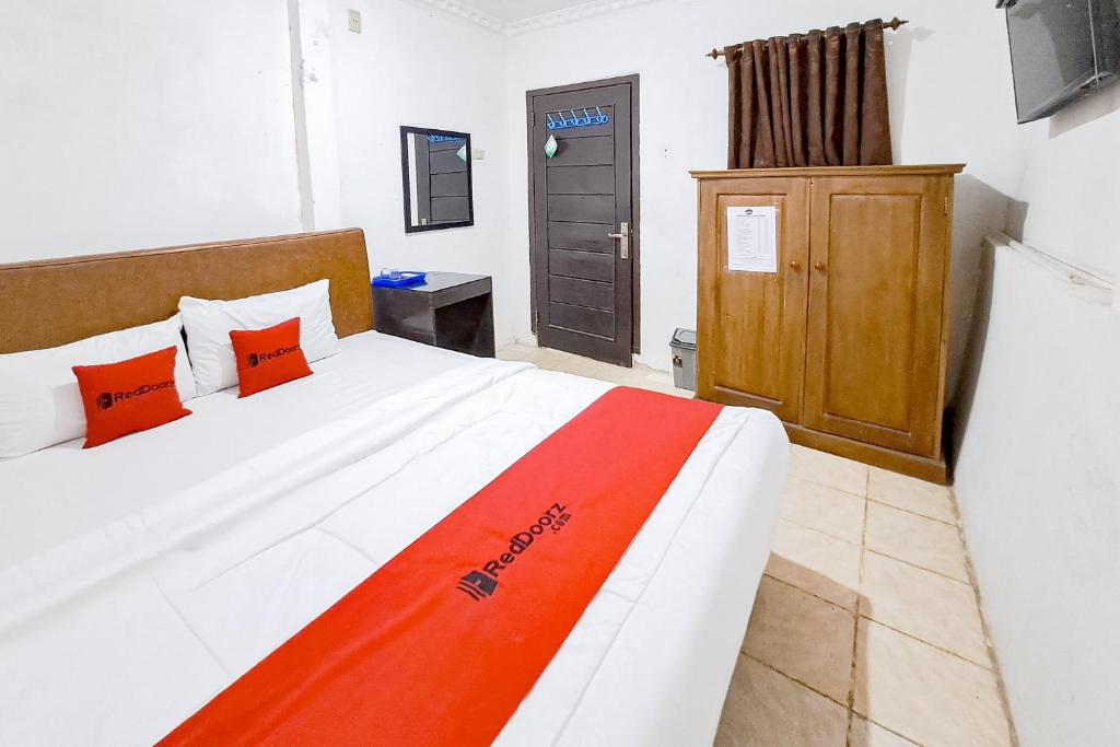 a bedroom with a bed with an orange and white blanket at RedDoorz at Lumungga Residence Lampung in Lampung