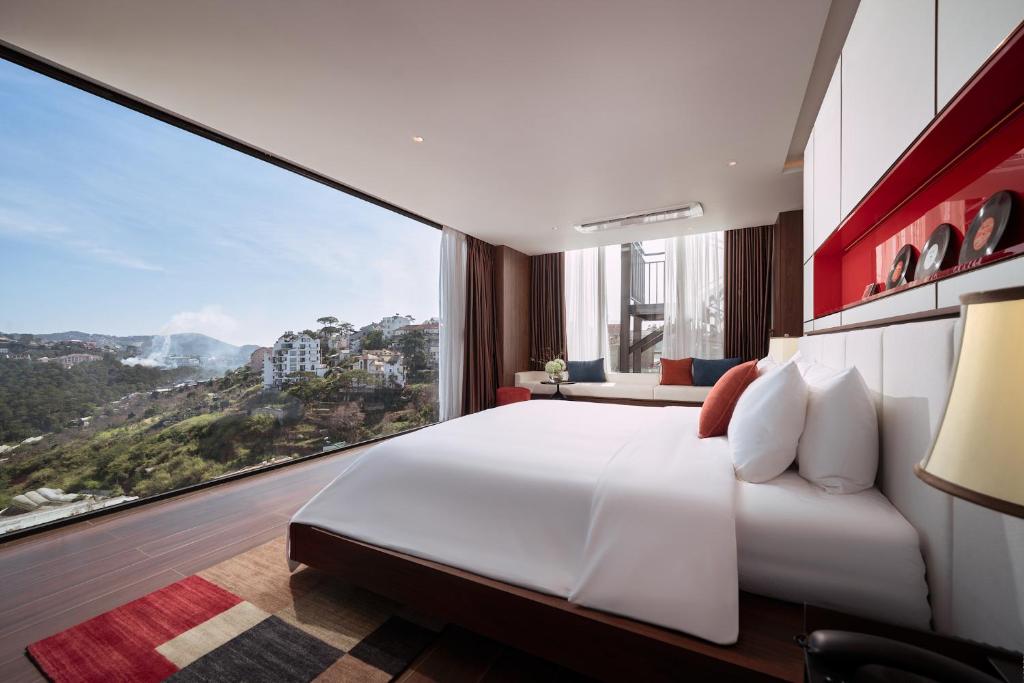a bedroom with a large white bed and a large window at CICILIA Rouge Dalat in Da Lat