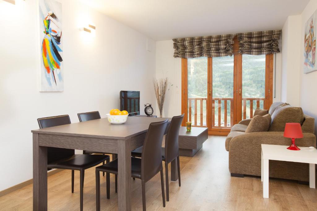 uma sala de estar com uma mesa e cadeiras e um sofá em Apartaments Les Terrasses del Tarter em El Tarter