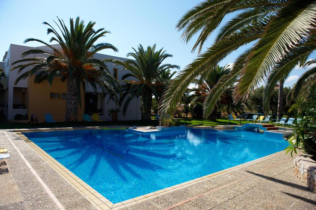 a large blue swimming pool with palm trees at Lycasti Maisonettes in Tavronitis