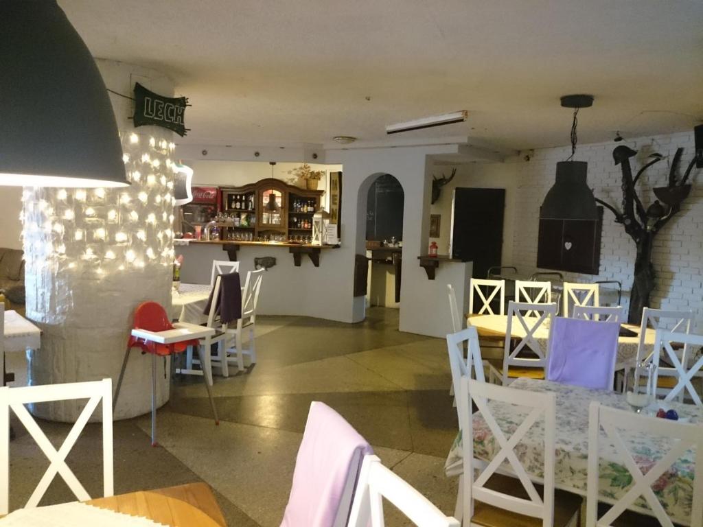 une salle à manger avec des tables et des chaises blanches dans l'établissement Kormoran, à Orzysz
