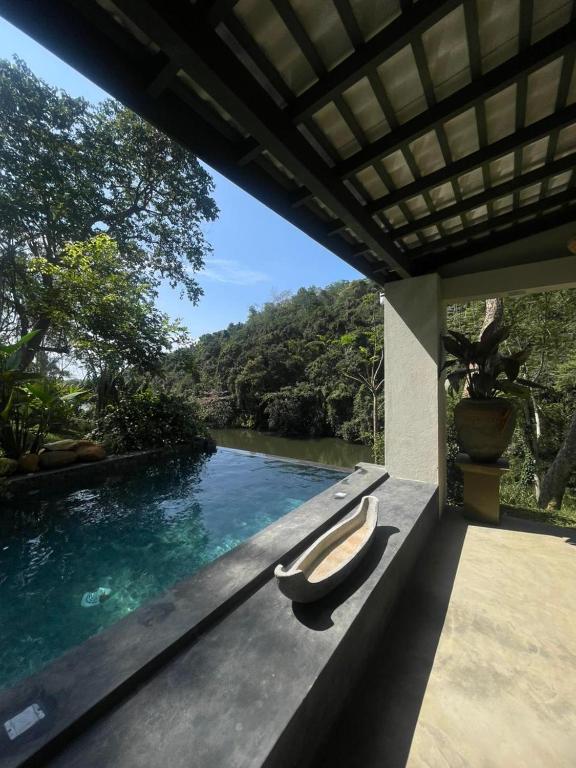 a swimming pool with a bench next to a river at Wanora Eco Villa in Dickwella