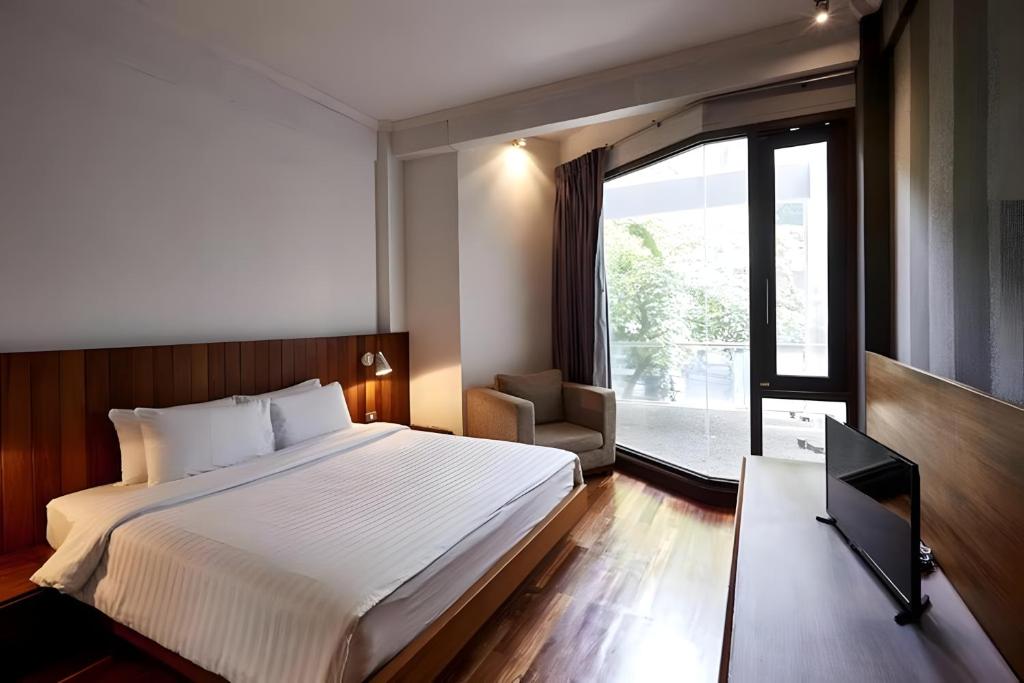 a hotel room with a bed and a window at Wish Inn Silom - Decho Bangkok City in Bang Rak