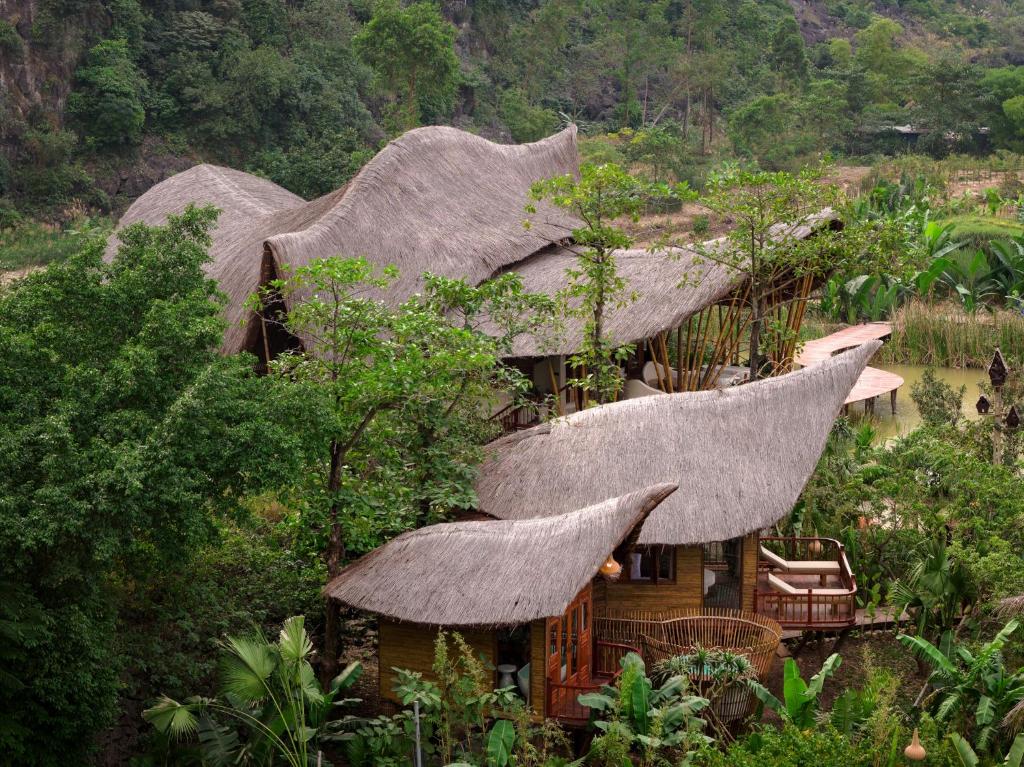 a small house with a thatched roof in a forest at Lamia Bamboo Retreat Ninh Binh in Ninh Binh