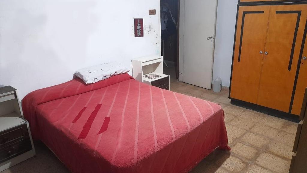 a bedroom with a red bed and a wooden cabinet at Habitacion en Casa de Olga in Alta Gracia