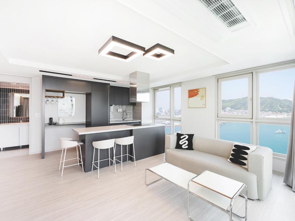 a kitchen and living room with a couch and a table at Elmomento Songdo in Busan