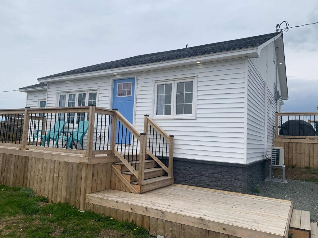 a small white house with a wooden deck at Spiller's Cottage in Twillingate