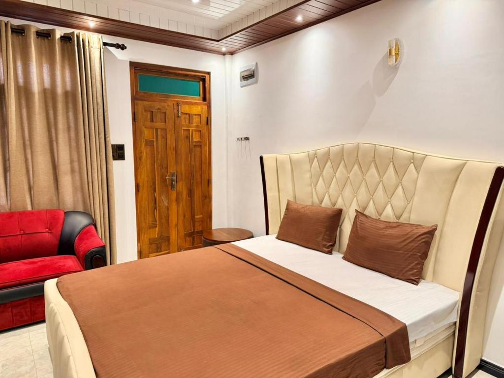 a bedroom with a bed and a red chair at Millennium Hotel in Jaffna