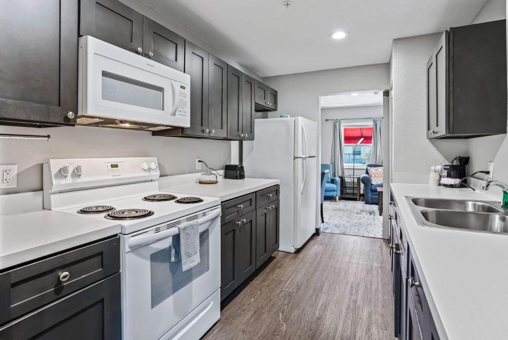 a kitchen with black cabinets and white appliances at Baymont by Wyndham Ocala Suites in Ocala