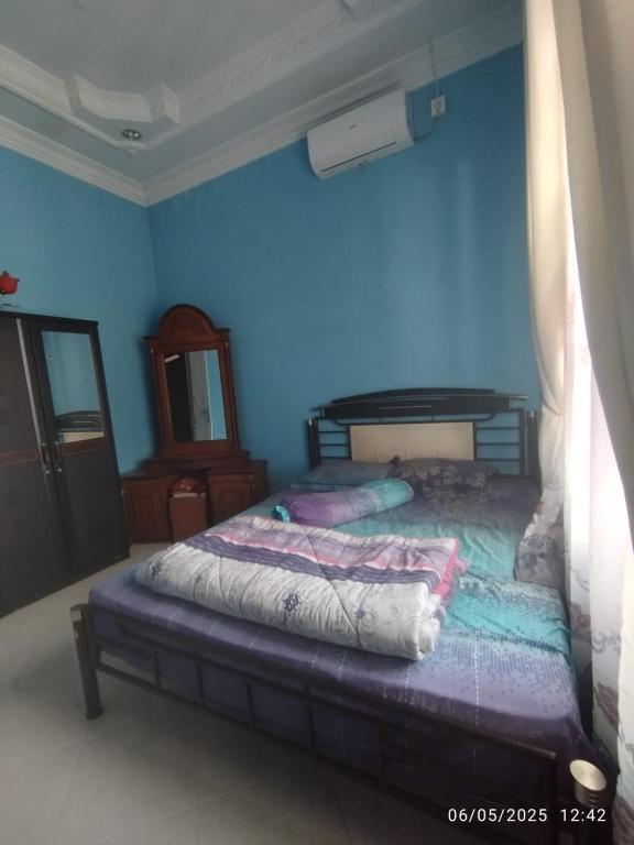 a bedroom with two beds in a blue wall at Penginapan Verlo in Payakumbuh