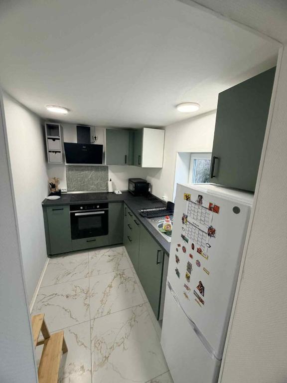 a small kitchen with green cabinets and a white refrigerator at Hel hus i rolig by in Birkelse