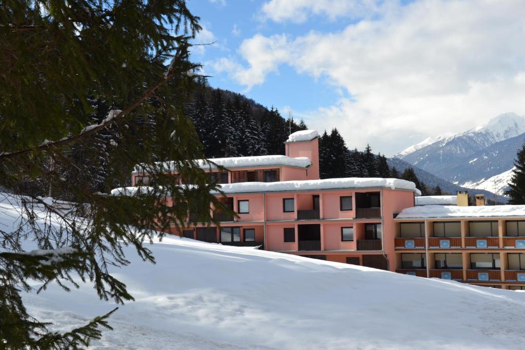 un bâtiment situé sur une pente enneigée en face d'une montagne dans l'établissement Residence Garden Appartamenti Solandra, à Mezzana