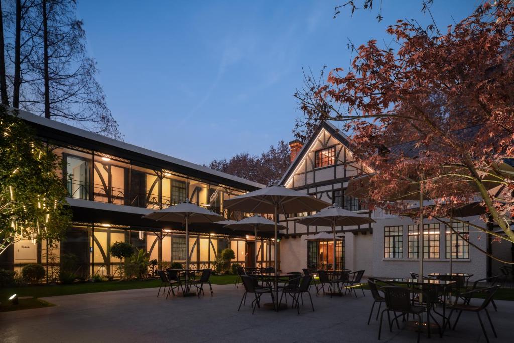 a building with tables and umbrellas in front of it at ANHE GARDEN HOTEL in Shanghai