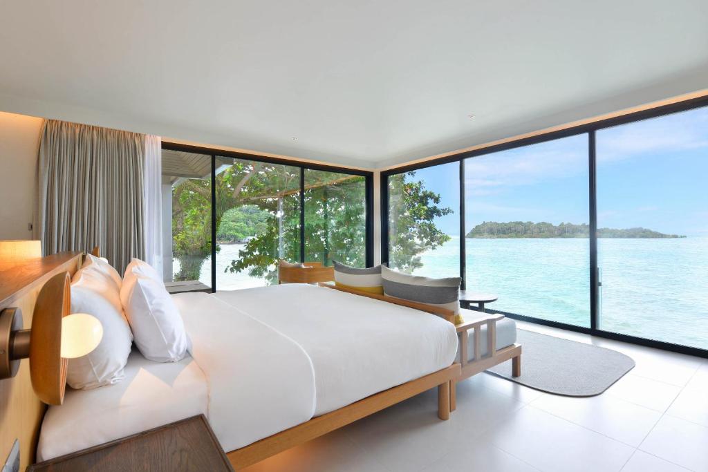 a bedroom with a large bed and large windows at SYLVAN Koh Chang in Ko Chang