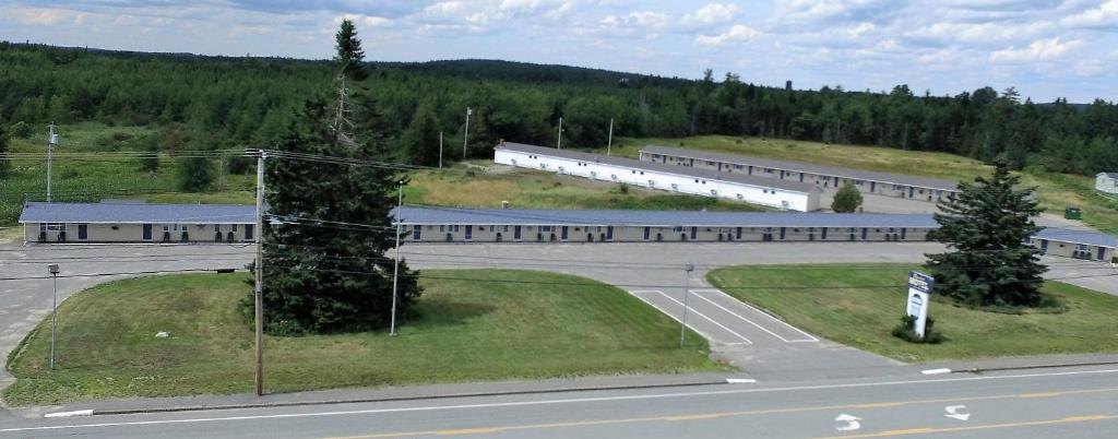 an aerial view of a building with a road and trees at The Bluebird Motel Maine in Machias