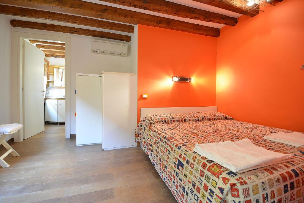 ein Schlafzimmer mit einem Bett und einer orangefarbenen Wand in der Unterkunft BARBERA-Biennale in Venedig