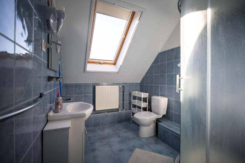 a bathroom with a toilet and a sink and a window at Czanadomb apartman in Cserkút