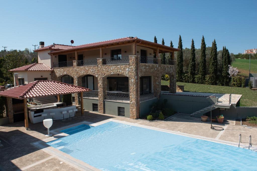a villa with a swimming pool in front of a house at Serenity Residence in Neoi Epivates