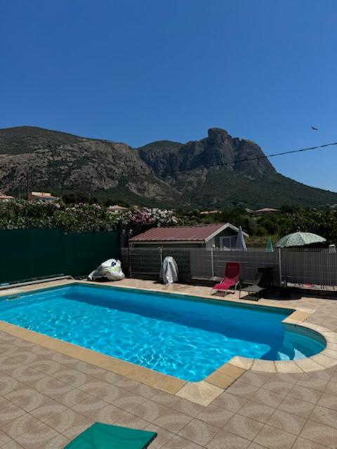 a blue swimming pool with a mountain in the background at Ribella in Appietto