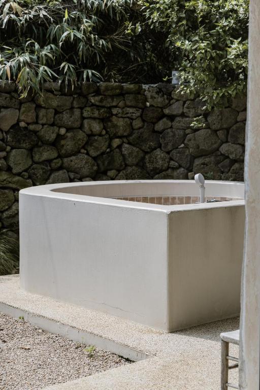 a white bath tub sitting next to a stone wall at 스테이스스와 야외자쿠지무료 in Sogil-li