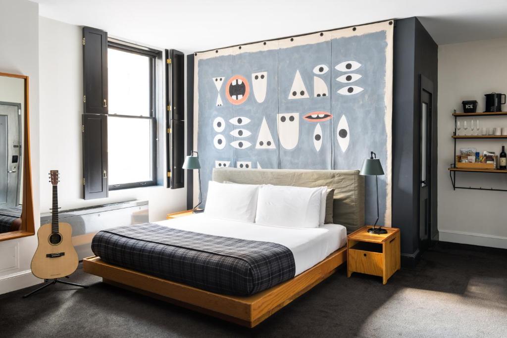 Un dormitorio con una cama y una guitarra. en Ace Hotel New York en Nueva York