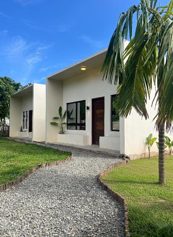 a white house with a palm tree in front of it at Lunara Villas in El Nido