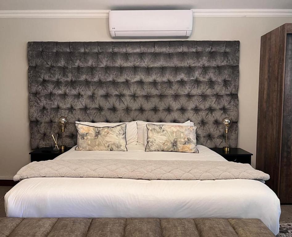 a bedroom with a large bed with a large headboard at Flamingo on Korsman in Benoni
