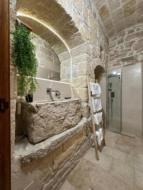 a stone bathroom with a sink and a shower at Room Pietra Bianca in Corato