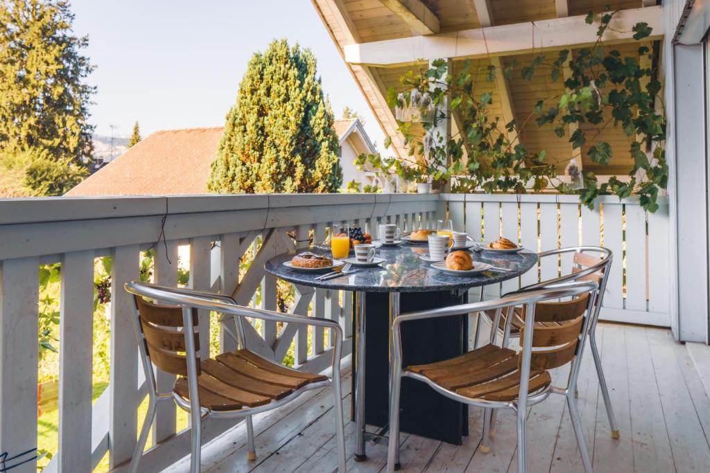 a table and chairs on a balcony with food on it at Armonia Altach, 2BR Familienapartment mit großem Balkon und Bergblick in Altach