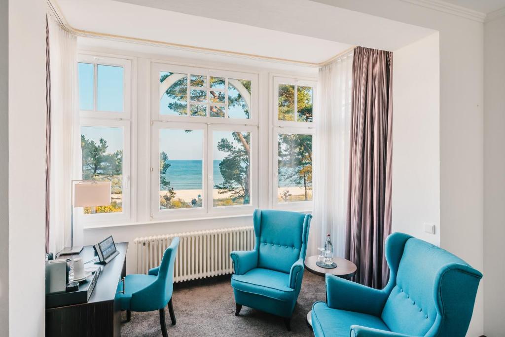 a room with blue chairs and a desk and a window at Hotel Villa Belvedere in Binz